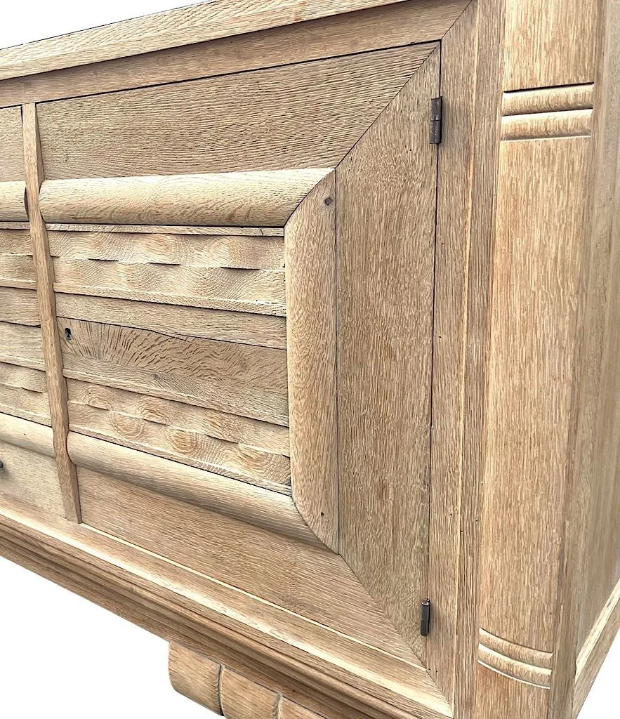 A French 1940s bleached oak sideboard in the style of Charles Dudouyt with two doors and four central drawers and relief front design