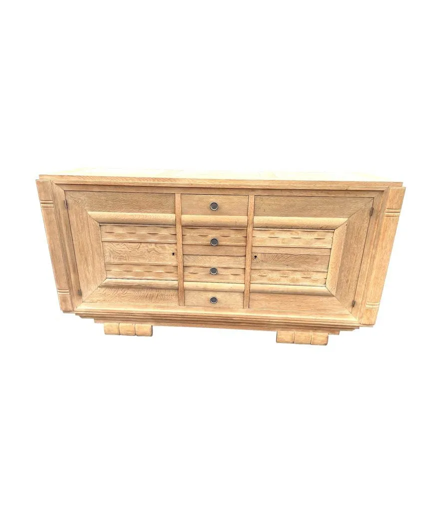 A French 1940s bleached oak sideboard in the style of Charles Dudouyt with two doors and four central drawers and relief front design