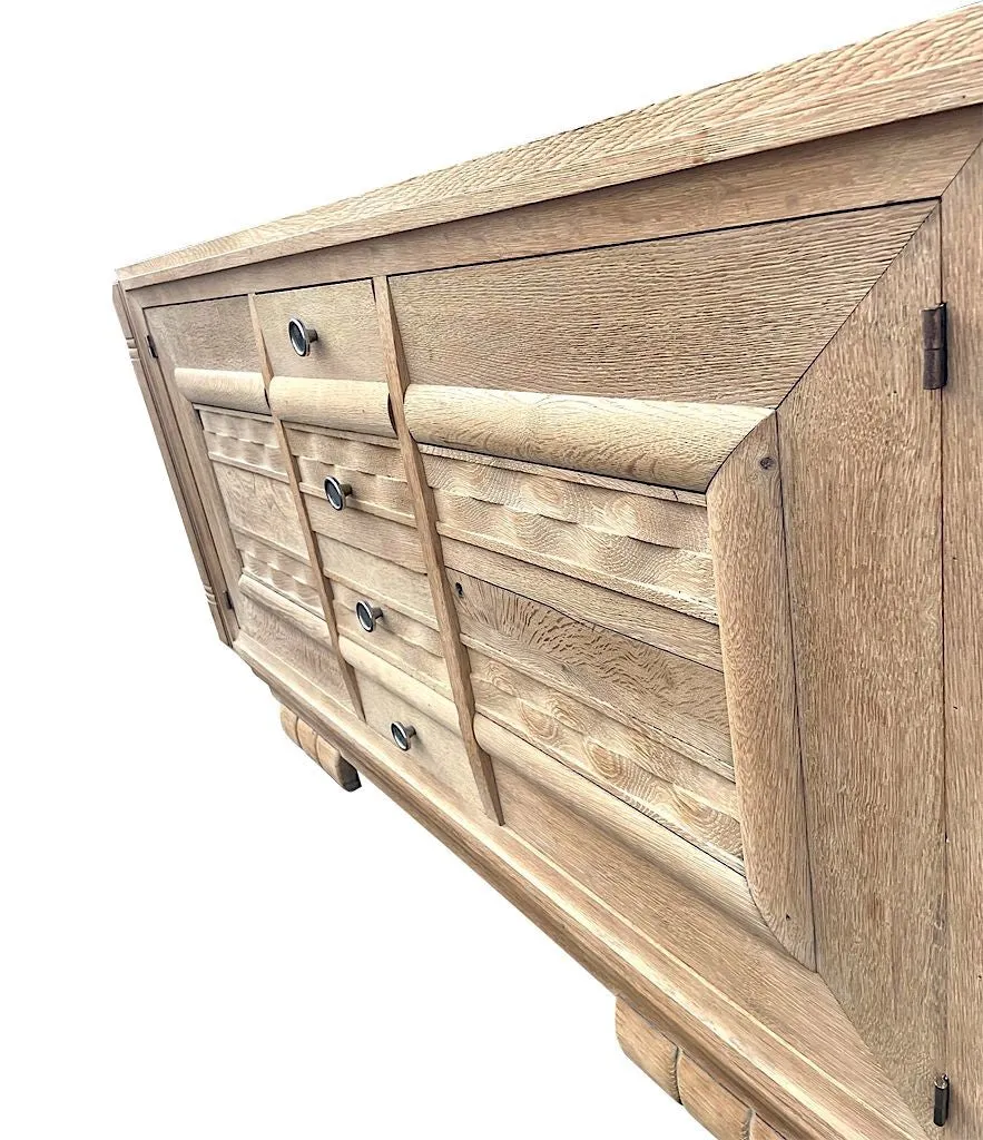 A French 1940s bleached oak sideboard in the style of Charles Dudouyt with two doors and four central drawers and relief front design