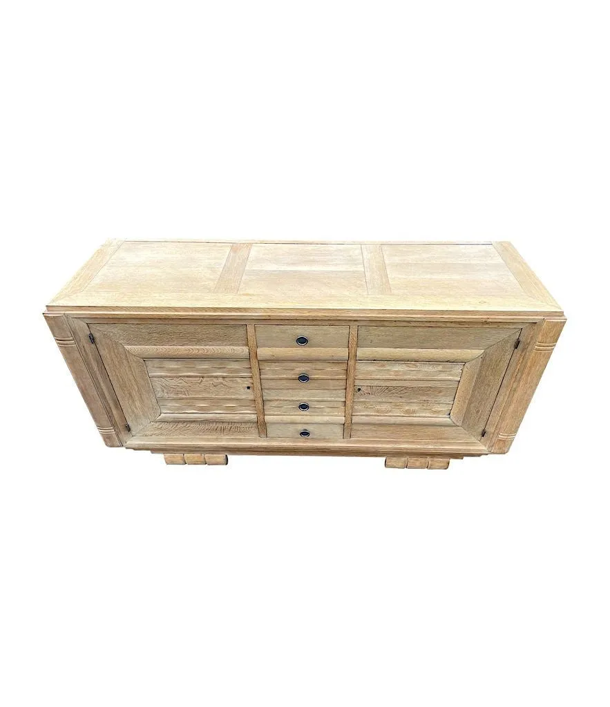 A French 1940s bleached oak sideboard in the style of Charles Dudouyt with two doors and four central drawers and relief front design