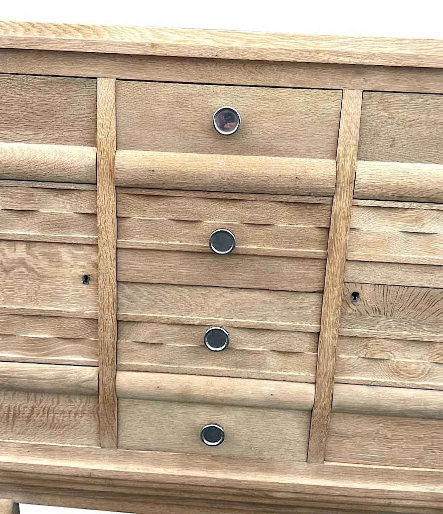 A French 1940s bleached oak sideboard in the style of Charles Dudouyt with two doors and four central drawers and relief front design